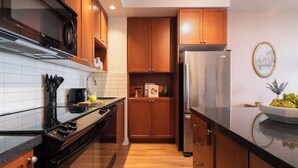 Une cuisine moderne avec des meubles en bois, un réfrigérateur en acier inoxydable et une cuisinière noire.