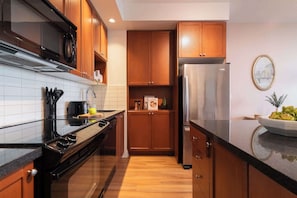 Eine moderne Küche mit Holzausstattung, einem Edelstahlkühlschrank und einem schwarzen Herd.