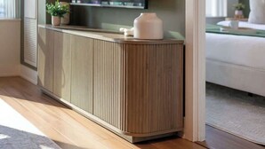 Un salon moderne avec un grand téléviseur à écran plat fixé à un meuble en bois, un canapé blanc et une petite plante en pot.