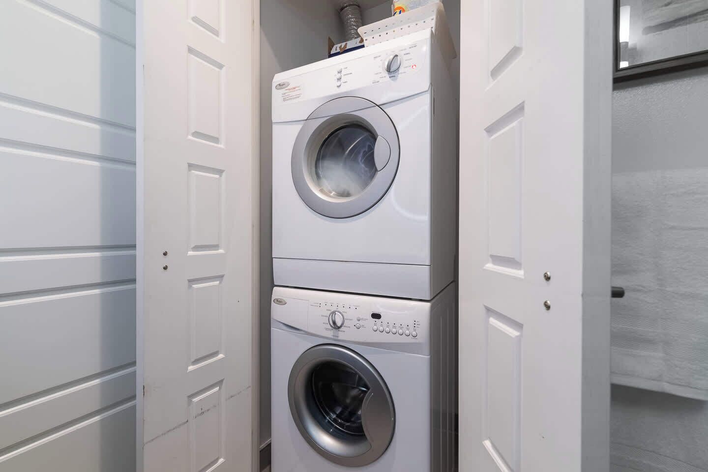 A stacked washer and dryer unit in a utility room.