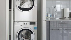Een kleine, moderne wasruimte met twee gestapelde wasmachines en een inbouwgootsteen.