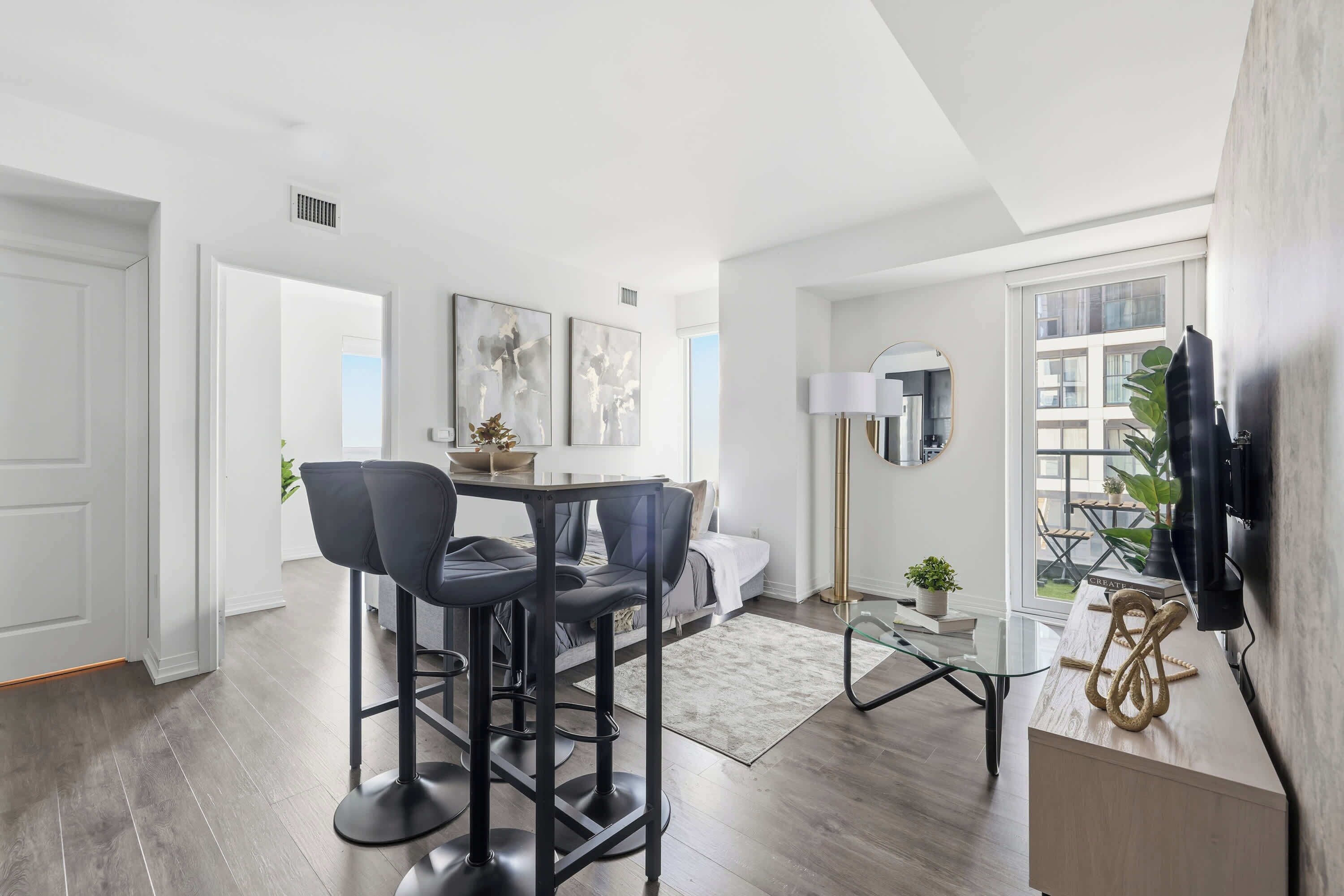 A modern living room with a dining area, a sofa, a coffee table, and a TV mounted on the wall.
