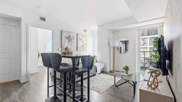 A modern living room with a dining area, a sofa, a coffee table, and a TV mounted on the wall.