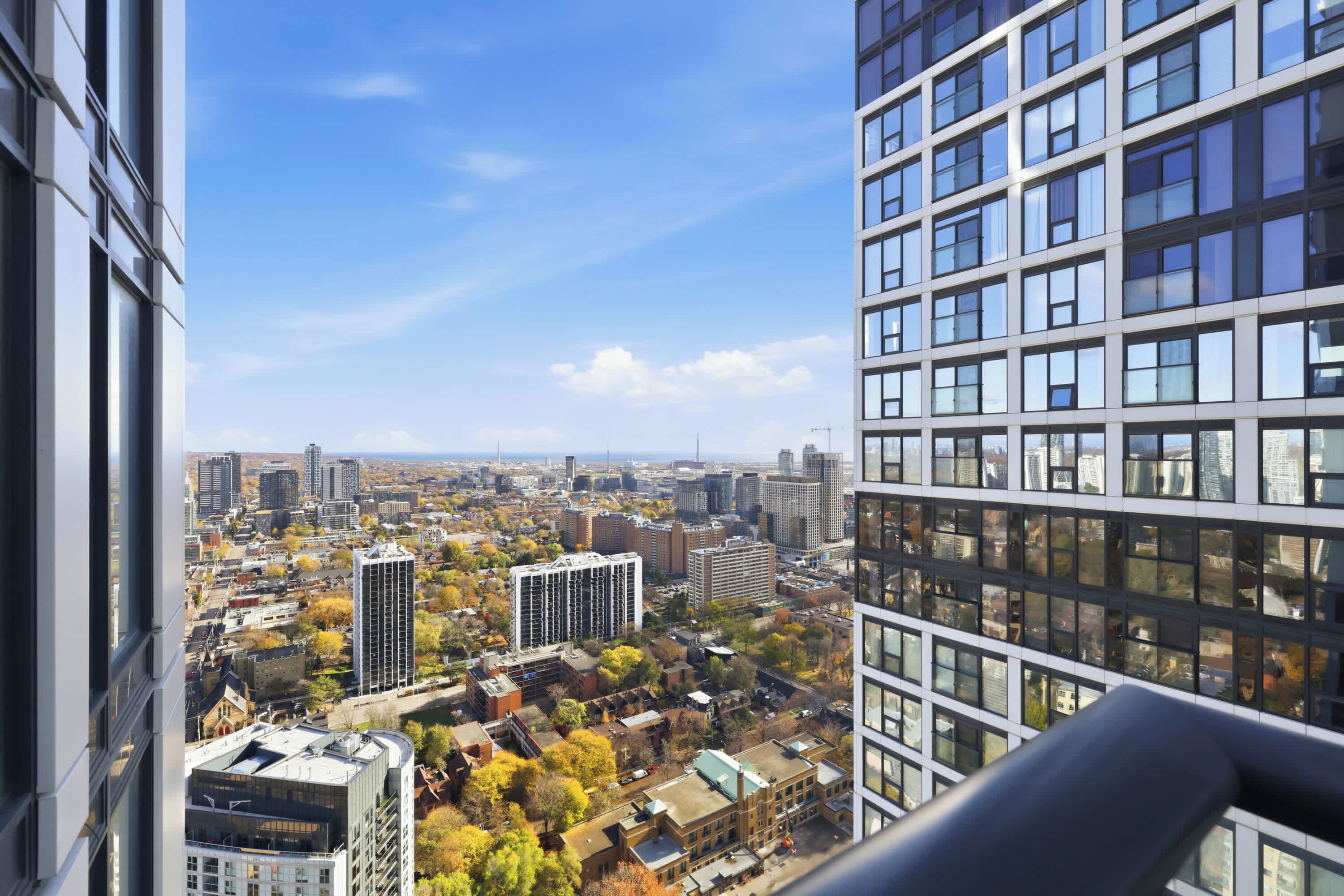 A high-rise building with multiple floors, large windows, and a view of a cityscape with various buildings and trees.