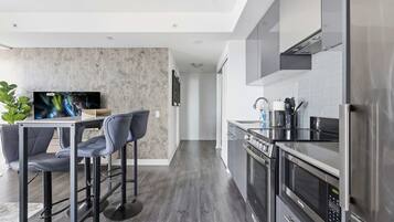 A modern kitchen with a dining area, stainless steel appliances, and a flat-screen TV.