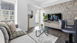 Een moderne woonkamer met een grote flatscreen televisie, een bank, een salontafel en een plant.