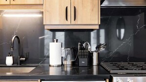 Una cucina con mobili in legno, un lavello in acciaio inossidabile, una macchina da caffè e un piano cottura.