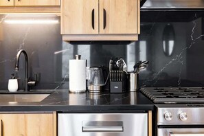 A kitchen with wooden cabinets, a stainless steel sink, a coffee maker, and a stove.