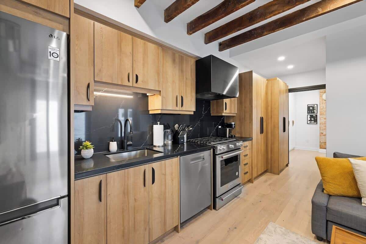 Eine moderne Küche mit Holzschränken, Edelstahlgeräten und einem eingebauten Backofen.