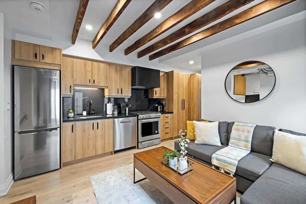Een moderne keuken met houten kastjes, roestvrijstalen apparatuur en een ronde spiegel aan de muur.