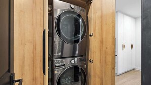 Una lavanderia con due lavatrici affiancate, una porta in legno e un armadio bianco sullo sfondo.