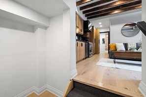 Une cuisine moderne avec des meubles en bois, un four encastré et un coin repas comprenant un canapé et une table basse.