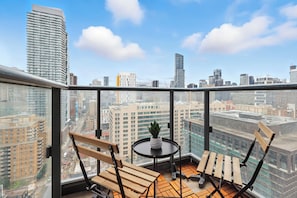 A balcony with two wooden chairs, a small table, and a potted plant. - Modern City Retreat in the Heart of Toronto | Parking Available (Toronto)