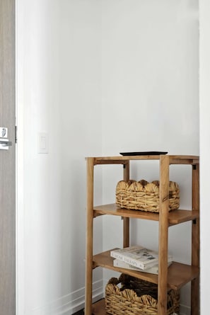 A corner of a room with a wooden shelf unit holding woven baskets and books. - Modern City Retreat in the Heart of Toronto | Parking Available (Toronto)