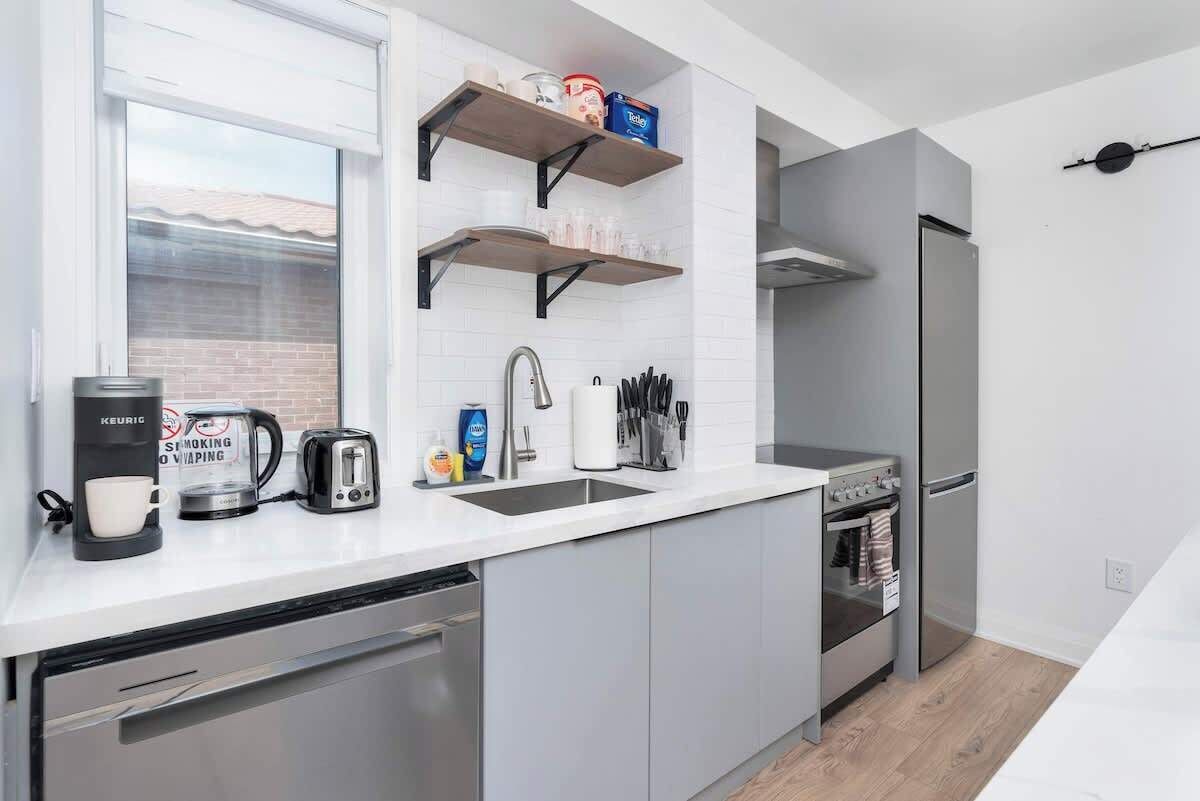 A modern kitchen with a dishwasher, a coffee maker, a toaster, and a stove.