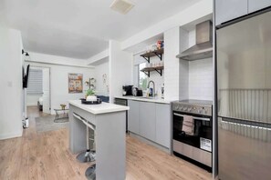 A modern kitchen with a central island, built-in oven, and stainless steel appliances.
