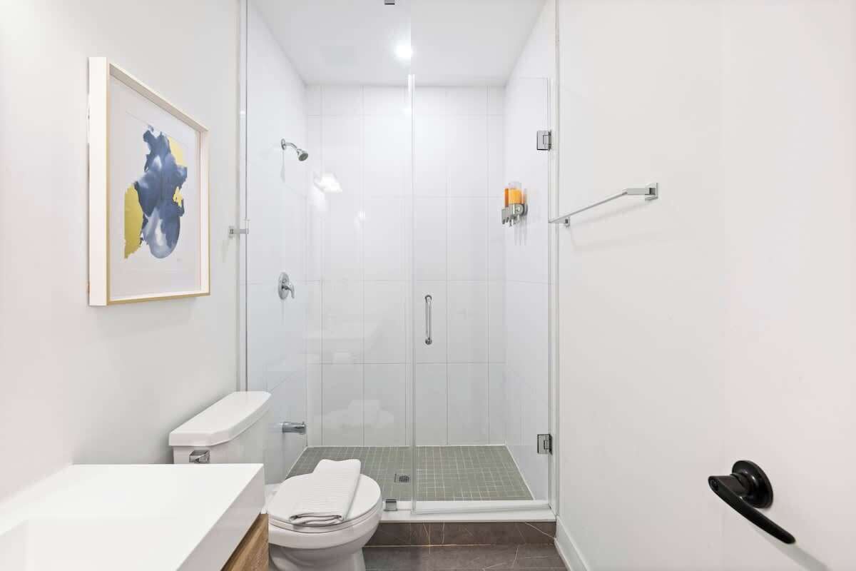 Een moderne badkamer met een glazen douchecabine, toilet en wastafel.