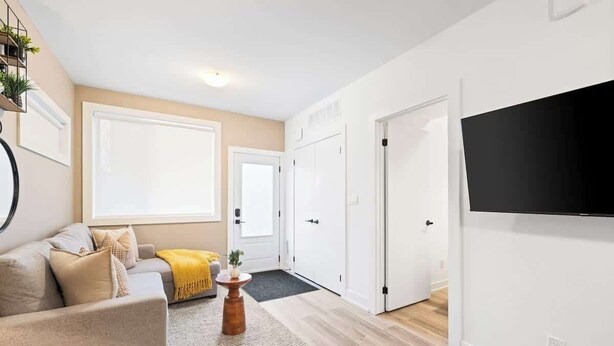 Una sala moderna con un sofá, una mesa de centro y un televisor de pantalla plana montado en la pared.