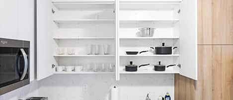 Une cuisine moderne avec des meubles blancs, un évier en acier inoxydable et un four à micro-ondes.