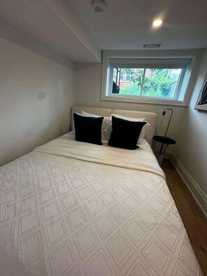 Een slaapkamer met een bed, een raam en een vloerlamp.