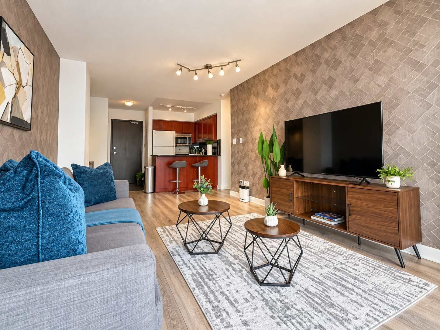 A modern living room with a sofa, coffee table, TV, and a kitchen in the background.