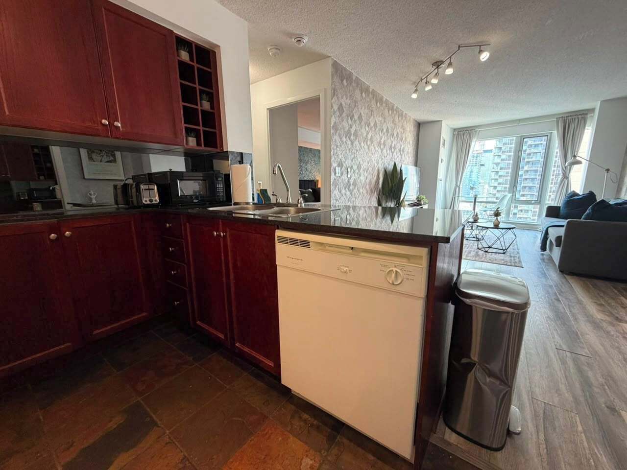 A modern kitchen with a dishwasher, a sink, and a trash bin.