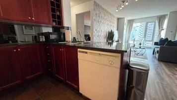 A modern kitchen with a dishwasher, a sink, and a trash bin.