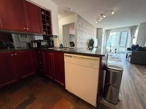 A modern kitchen with a dishwasher, a sink, and a trash bin.