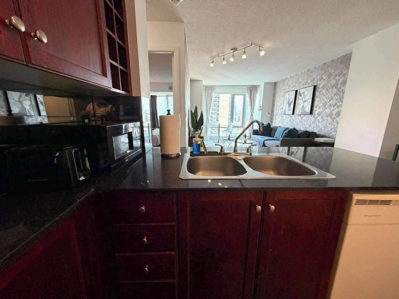 A kitchen with a double sink, dark wooden cabinets, and a modern countertop.