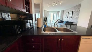 A kitchen with a double sink, dark wooden cabinets, and a modern countertop.