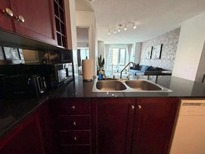 A kitchen with a double sink, dark wooden cabinets, and a modern countertop. - Downtown King Retreat | Walk to Yonge Sq (Toronto)