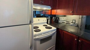 A kitchen with a white refrigerator, stove, and oven, wooden cabinets, and a granite countertop.