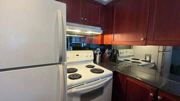 A kitchen with a white refrigerator, stove, and oven, wooden cabinets, and a granite countertop.