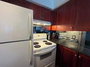 A kitchen with a white refrigerator, stove, and oven, wooden cabinets, and a granite countertop.