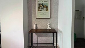 A framed artwork of Paul Cezanne's 'The Basket of Apples' on a wall above a dark wooden table with two white vases.