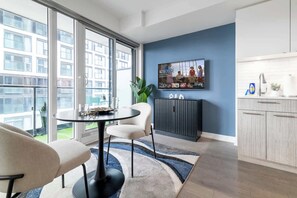 Ein modernes Wohnzimmer mit Essbereich, einem an der Wand montierten Fernseher und Blick ins Freie.