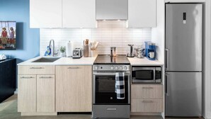 Una cocina moderna con un refrigerador de acero inoxidable, horno empotrado, microondas y estufa a gas.