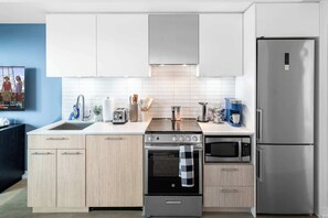 Eine moderne Küche mit einem Edelstahl-Kühlschrank, einem eingebauten Backofen, einer Mikrowelle und einem Gasherd.