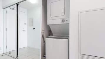 Une buanderie équipée d’un lave-linge et d’un sèche-linge à chargement frontal, d’une porte-fenêtre coulissante et d’un sol carrelé.