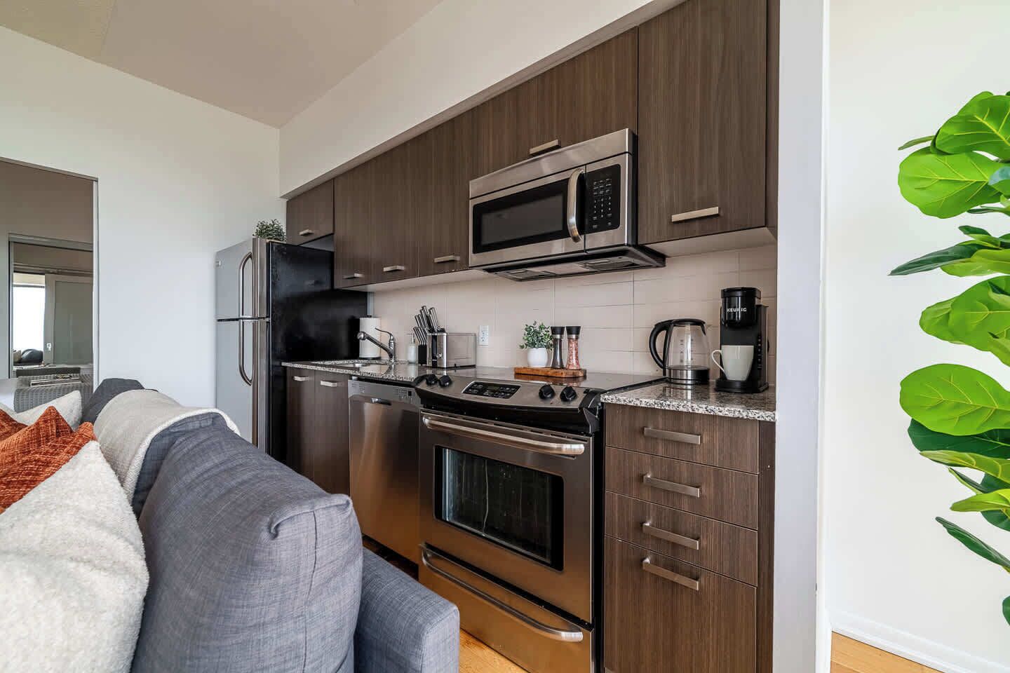 Une cuisine moderne dotée d’appareils électroménagers en acier inoxydable, de meubles en bois et d’un four à micro-ondes encastré.