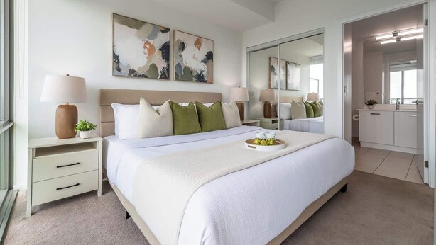 A modern bedroom with a large bed, bedside tables, a mirror, and artwork on the wall. - Financial District 3BR CN Tower Views! (Toronto)