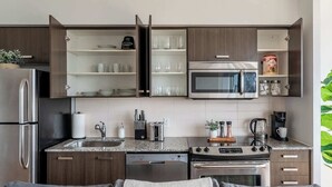 A modern kitchen with a built-in microwave, stainless steel appliances, and open shelving. - Financial District 3BR CN Tower Views! (Toronto)