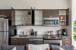 Eine moderne Küche mit Einbau-Mikrowelle, Edelstahlgeräten und offenen Regalen.