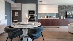 A modern kitchen with a central island, a dining area with a round table, and a living space with a sofa. - Upscale 3BR Downtown Suite with Parking! (Toronto)