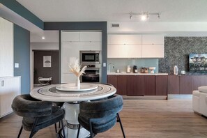 Eine moderne Küche mit Kochinsel, ein Essbereich mit rundem Tisch und ein Wohnbereich mit einer Couch.