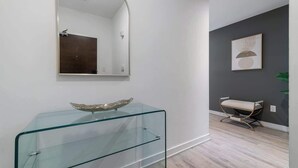 A modern bathroom with a glass vanity, a large mirror, and a dark accent wall. - Upscale 3BR Downtown Suite with Parking! (Toronto)