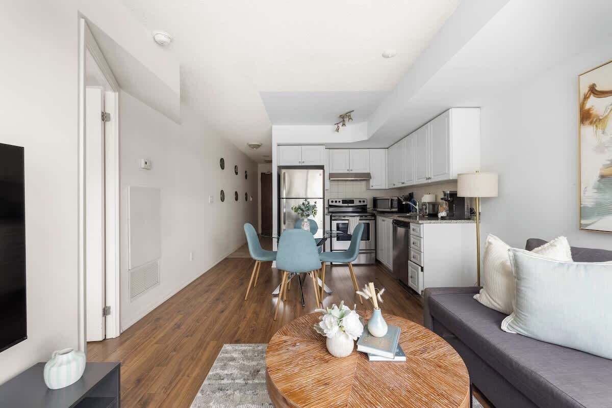 Uma sala de estar moderna com um sofá, uma mesa de centro e um espaço de refeições com cadeiras.