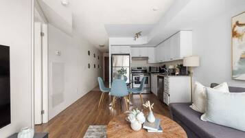 Uma sala de estar moderna com um sofá, uma mesa de centro e um espaço de refeições com cadeiras.