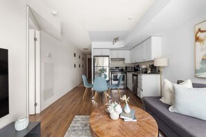 A modern living room with a sofa, a coffee table, and a dining area with chairs.