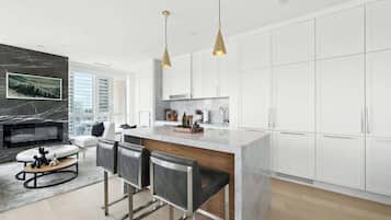 A modern kitchen with white cabinets, a marble island, and pendant lighting.